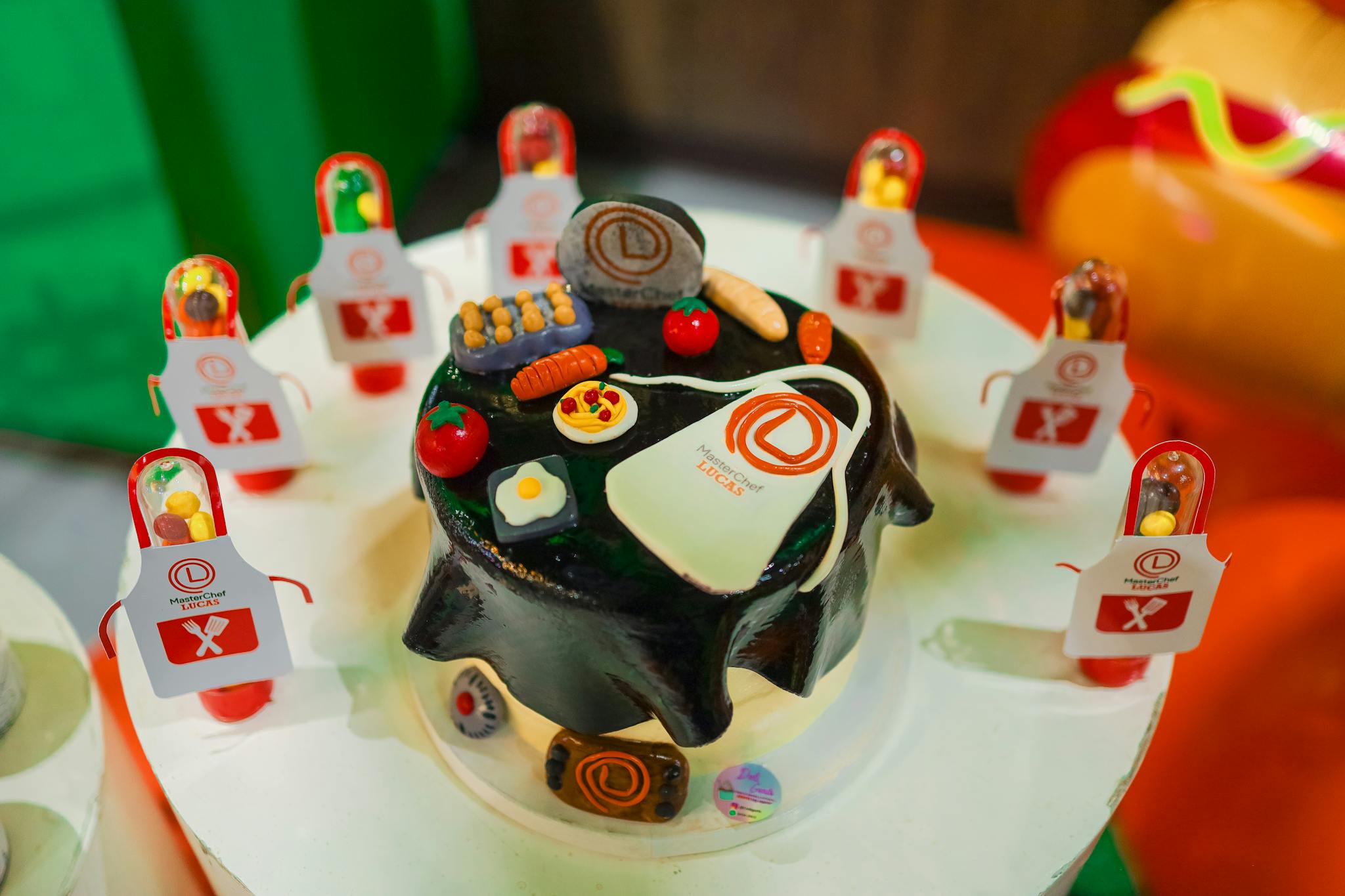 A vibrant chef-themed cake decorated with edible miniatures and aprons, perfect for culinary celebrations.