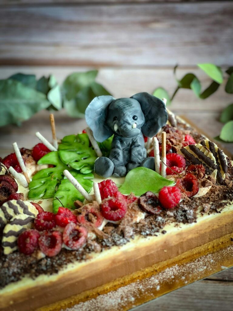 Decorated cake with elephant figure and fresh berries, perfect for special occasions.